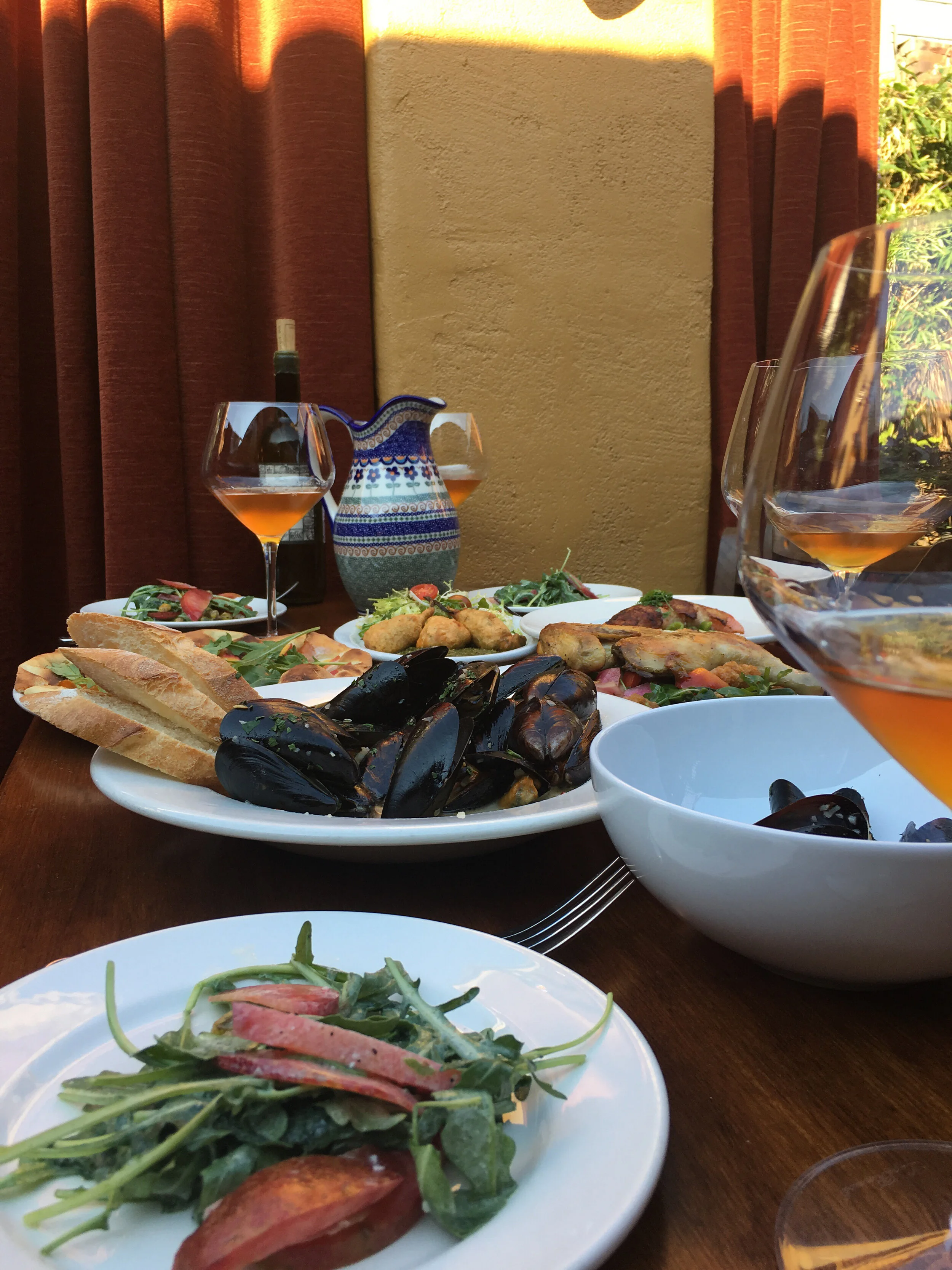 Shared plates with mussels, bread, salad and wine pictured on À Côté’s website